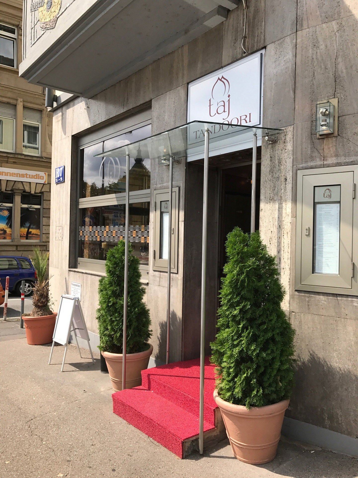 Eingang des Taj Tandoori Mannheim in R7 mit rotem Teppich und Pflanzen
